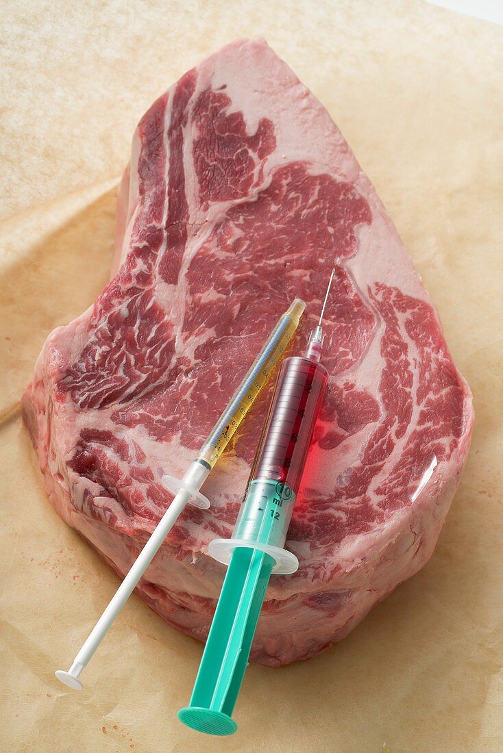 Raw beef steak with syringes (food additives)