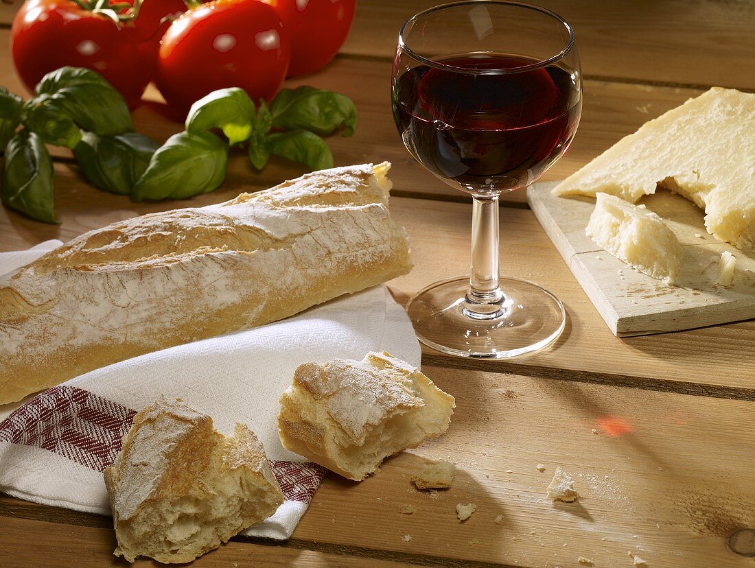 Still life: bread, Parmesan, glass of red wine, basil, tomatoes