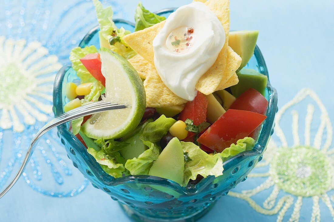 Mexican salad with nachos, sour cream and lime
