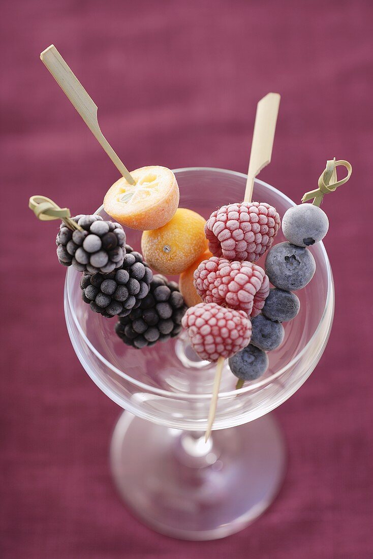 Frozen fruit skewers in an empty champagne saucer