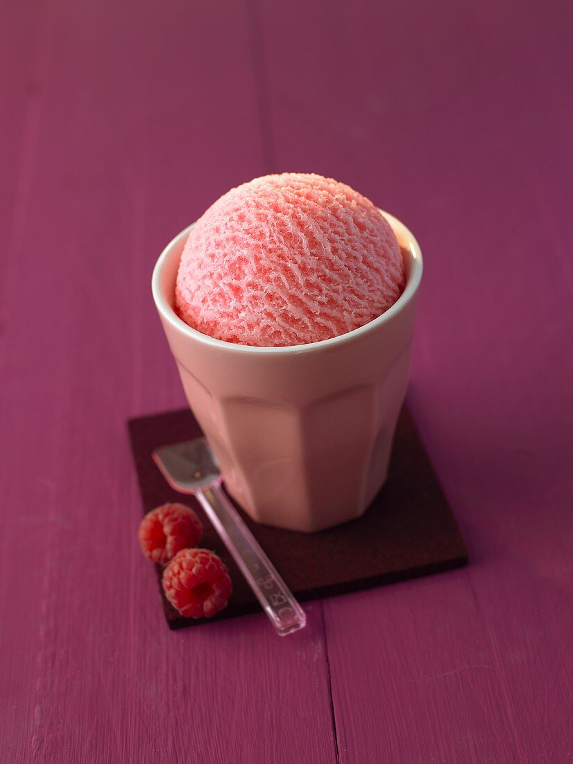 A scoop of raspberry ice cream in a pink beaker