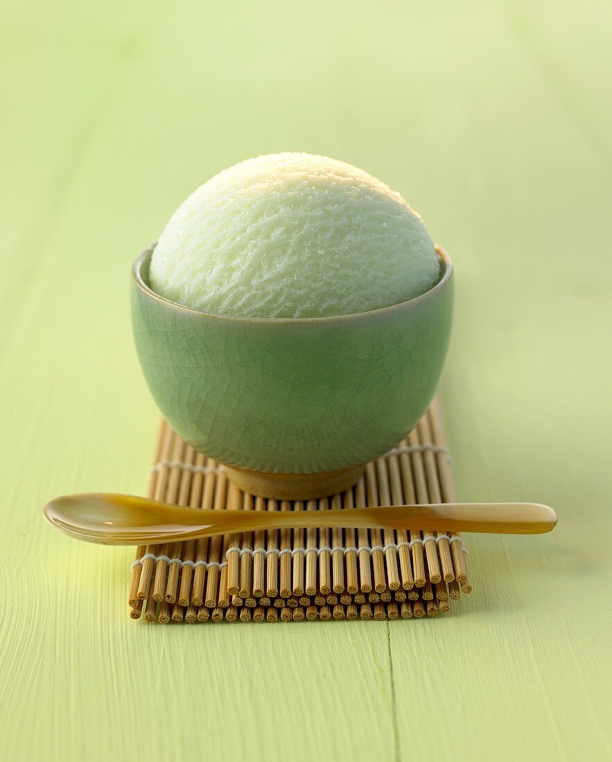 Eine Kugel Teeeis in grünem Schälchen auf Bambusmatte