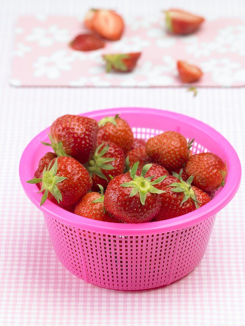 Fresh strawberries in pink plastic strainer