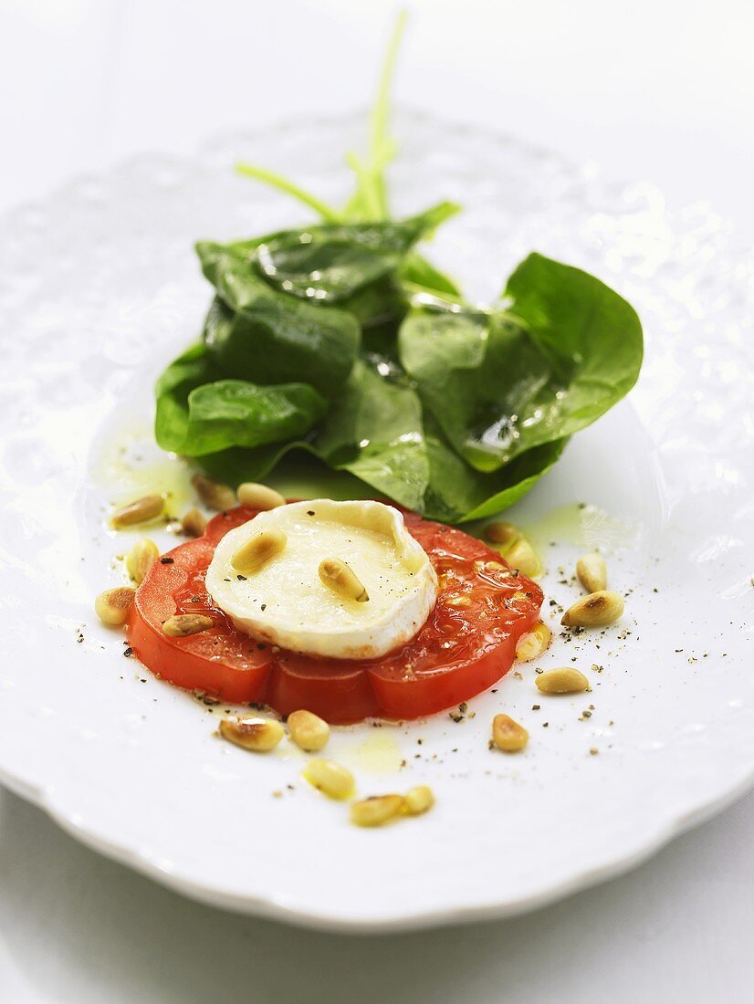 Goat's cheese on tomato with pine nuts and spinach