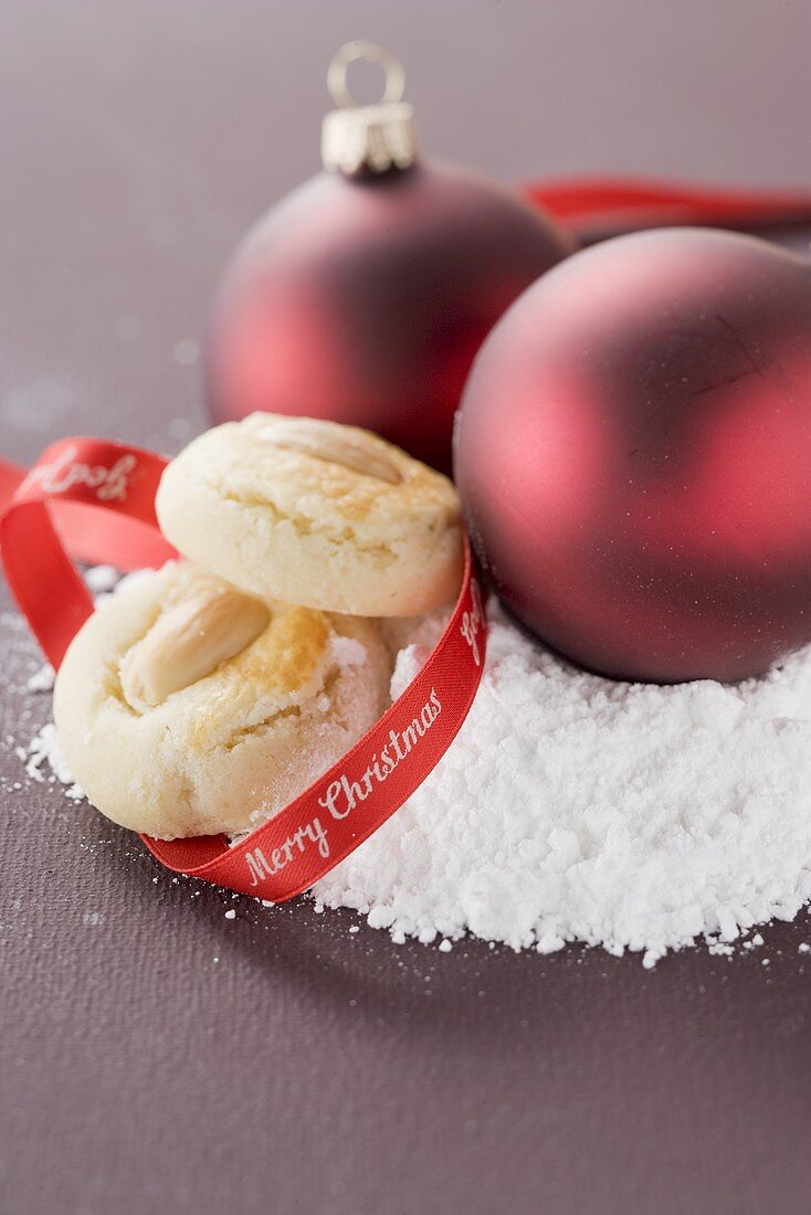Almond biscuits and Christmas baubles on icing sugar