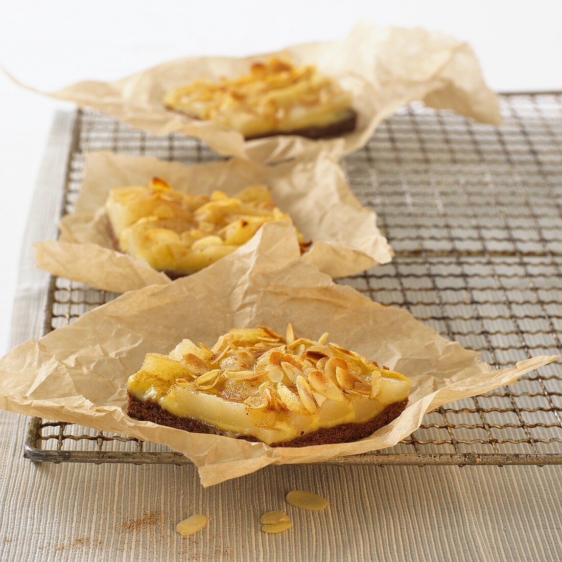 Small pear tarts with flaked almonds on baking parchment