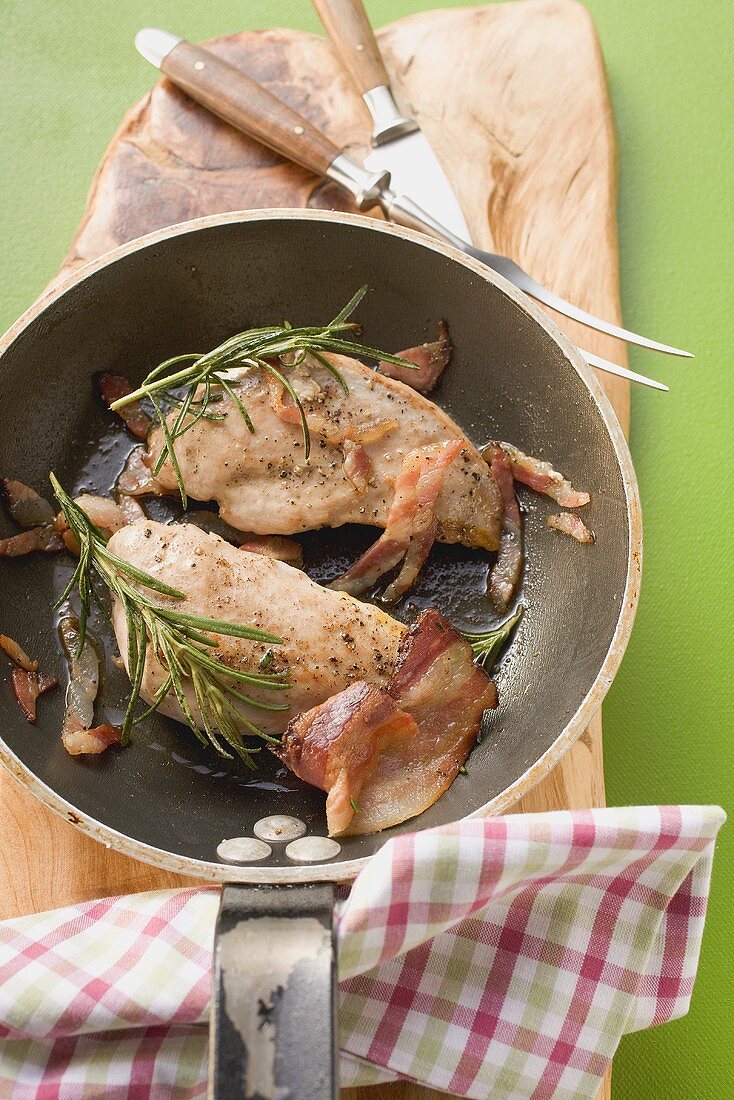 Pheasant breast with bacon and rosemary in frying pan