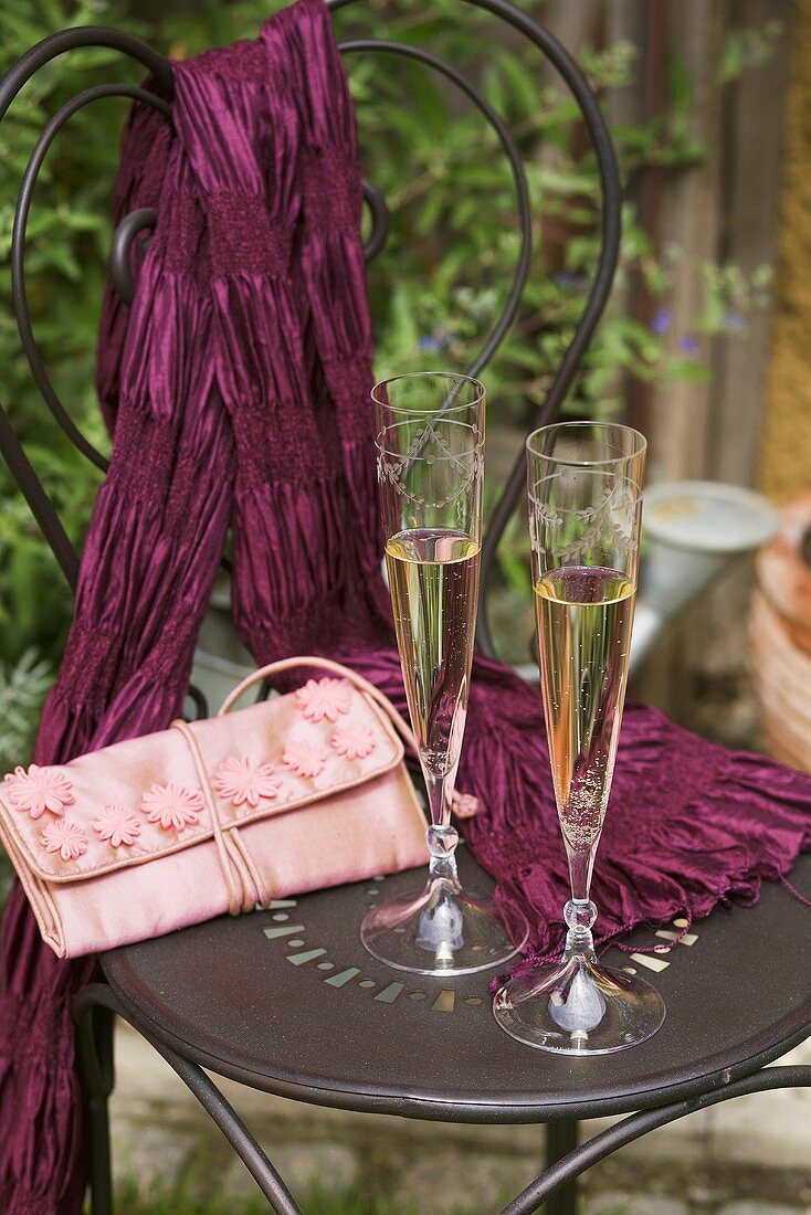 Two champagne flutes on garden chair