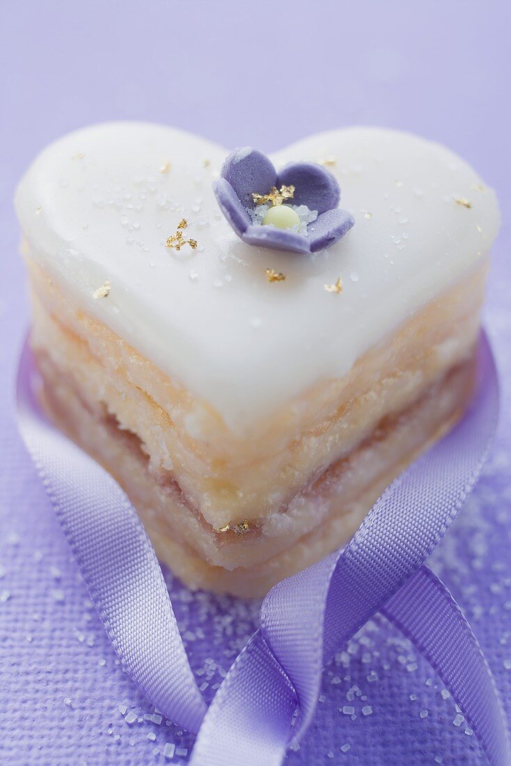 Small heart-shaped cake with sugar flower, gold and ribbon