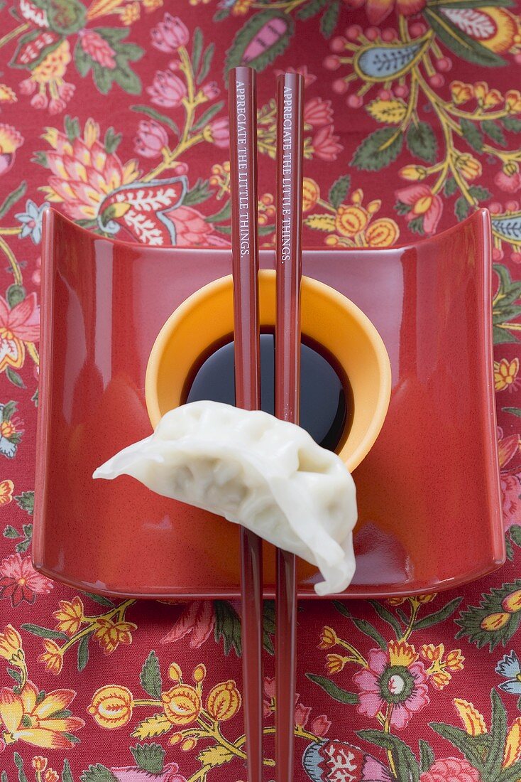 Soy sauce in small dish, chopsticks and wonton on dish