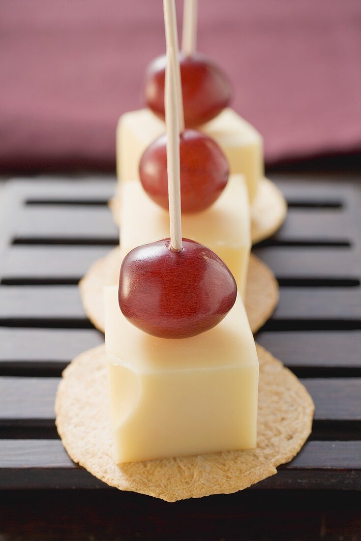 Cheese and grapes on cocktail sticks on crackers