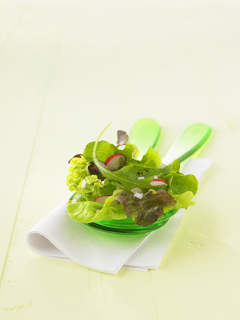 Mixed salad leaves with radishes on salad servers