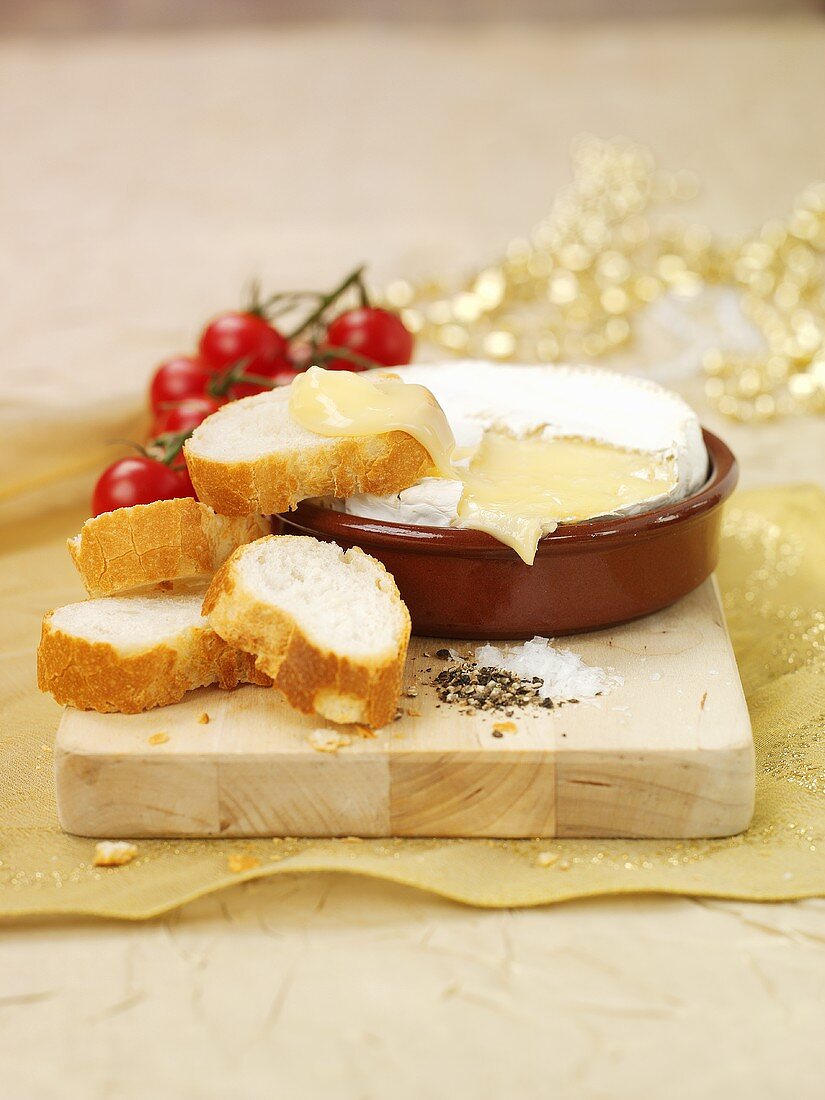 Camembert in terracotta dish with baguette slices