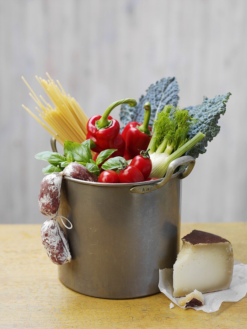 Gemüse, Spaghetti und Minisalamis im Kochtopf, daneben Käse