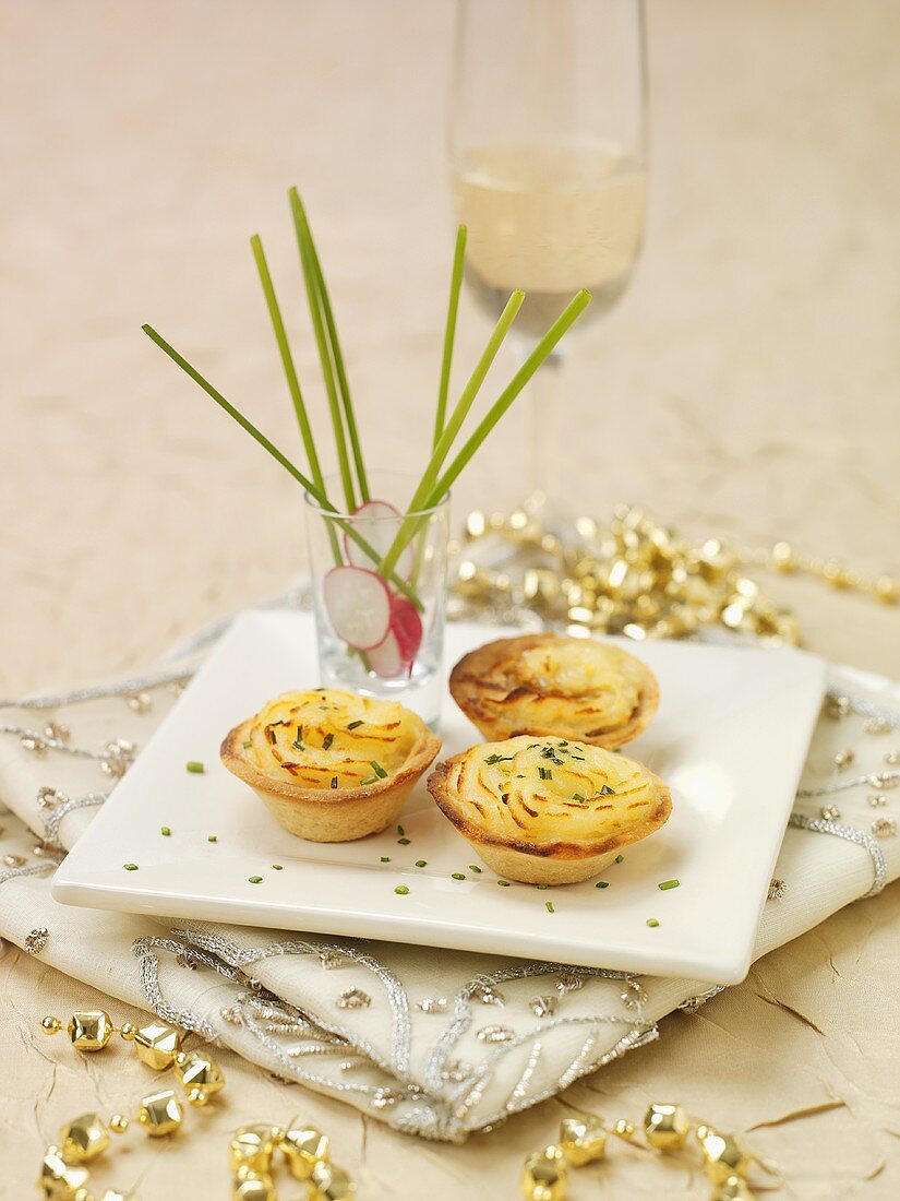 Minipies mit Kartoffelpüree und Fisch, Sekt im Hintergrund