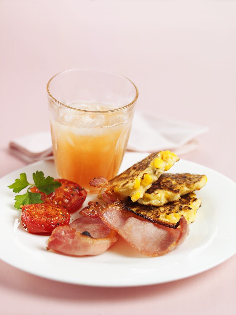 Sweetcorn cakes with bacon & tomato, glass of fruit juice