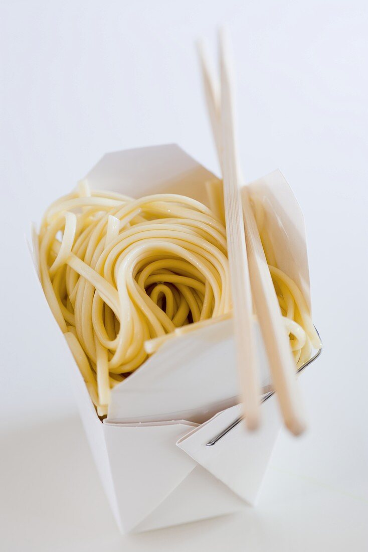 Noodles in take-away box with chopsticks