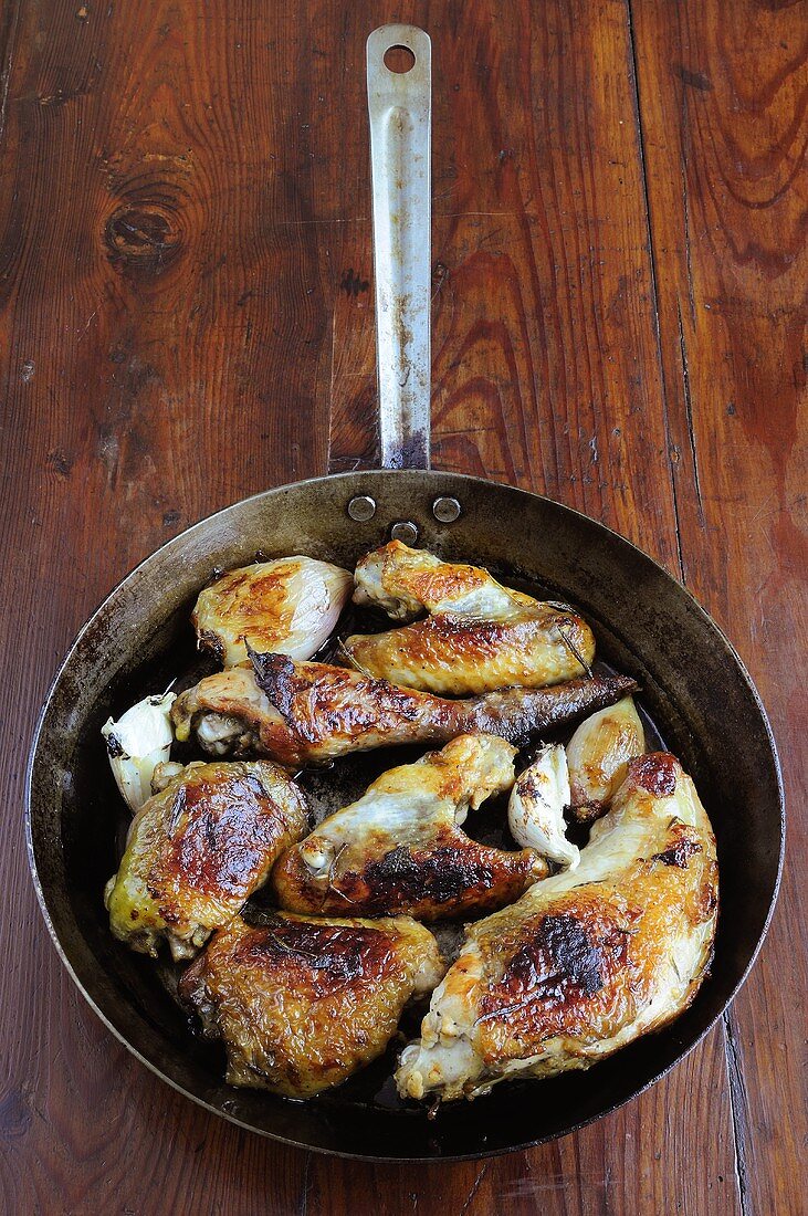 Fried guinea fowl pieces in a frying pan