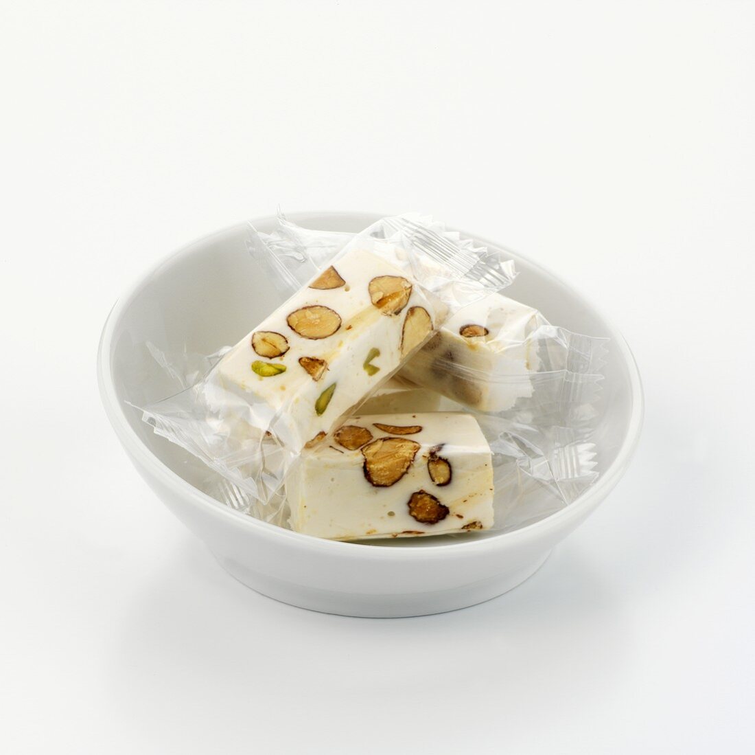 Individually packed pieces of almond nougat in white bowl