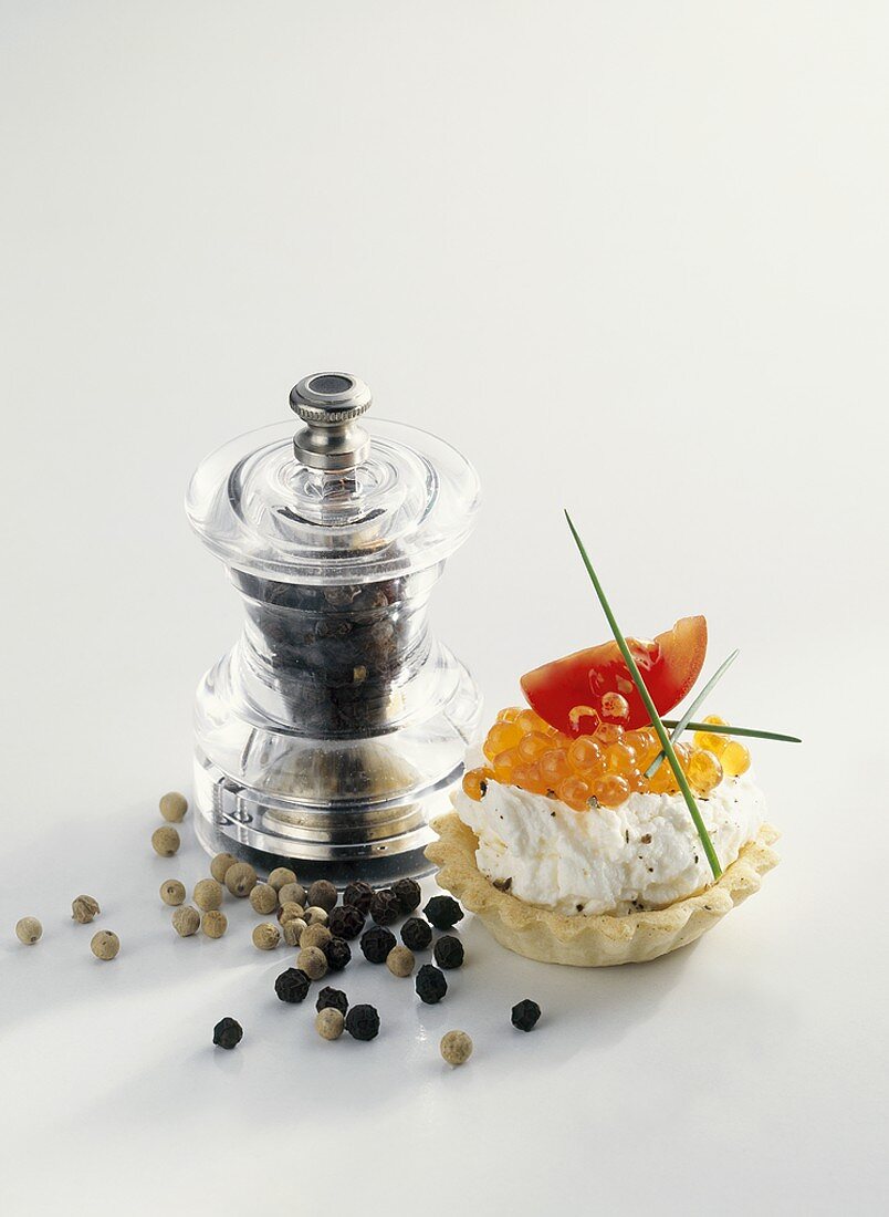 Soft cheese and trout caviar in tart shell, pepper mill