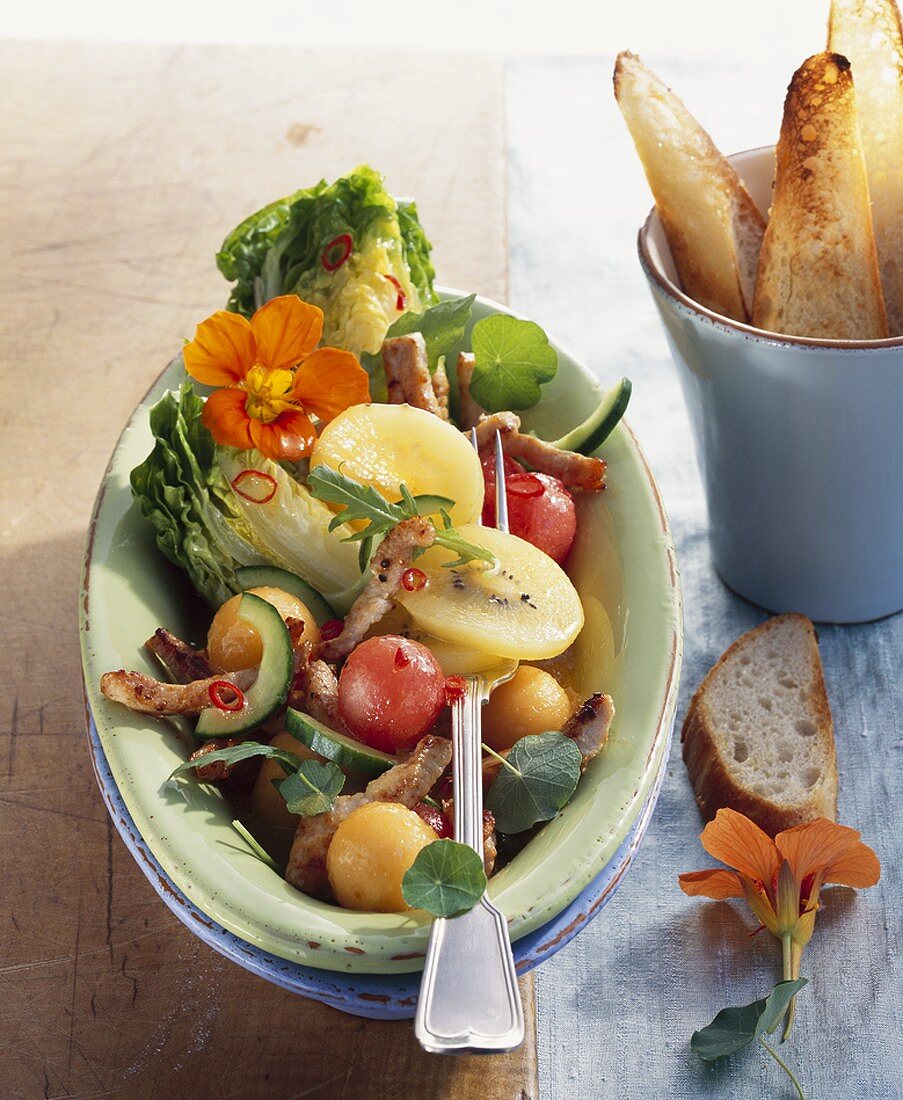 Savoury melon salad with strips of turkey, baguette