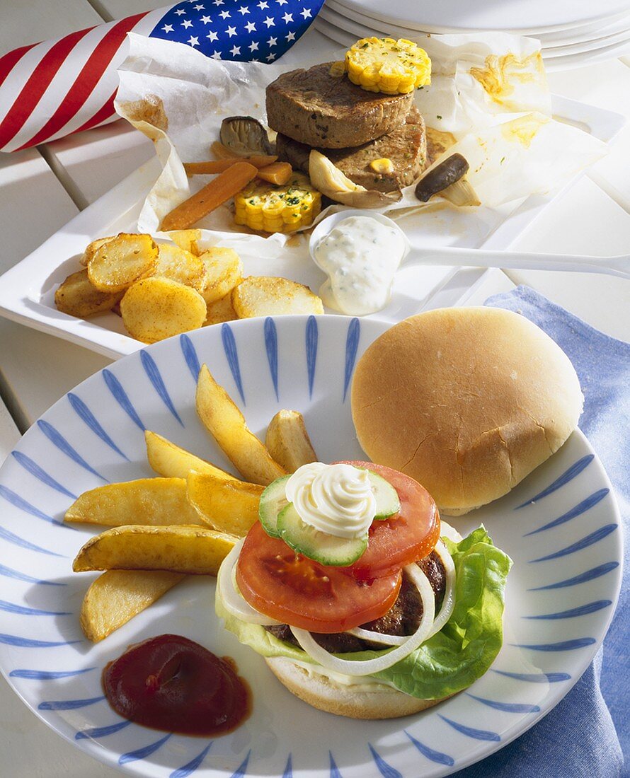 Hamburger mit Potato Wegdes, im Hintergrund Filetsteak mit Mais (USA)