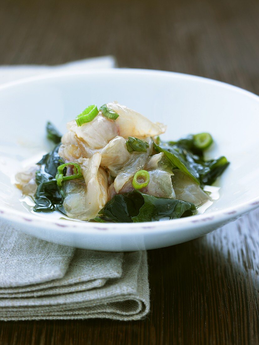 Raw fish fillets with seaweed and spring onions
