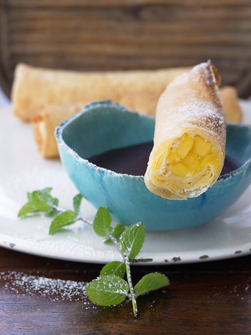 Sweet spring rolls with mango filling and chocolate sauce