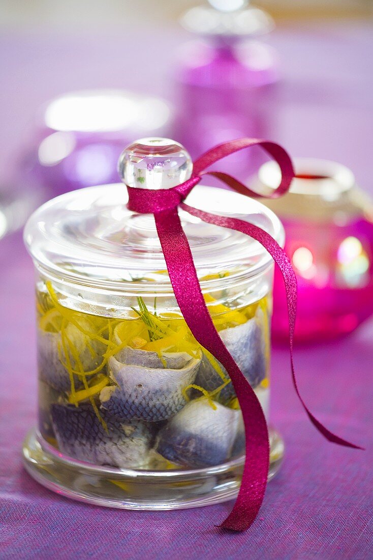 Pickled herrings with lemon zest in jar with gift ribbon