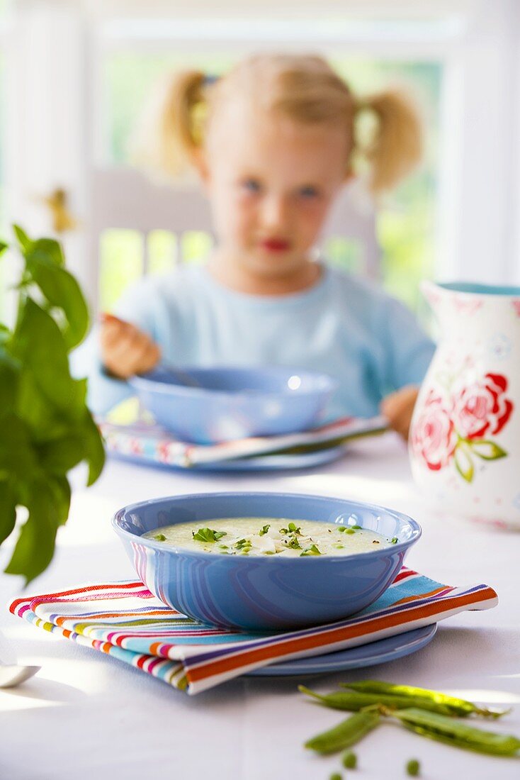 Potato soup on laid table, child in background