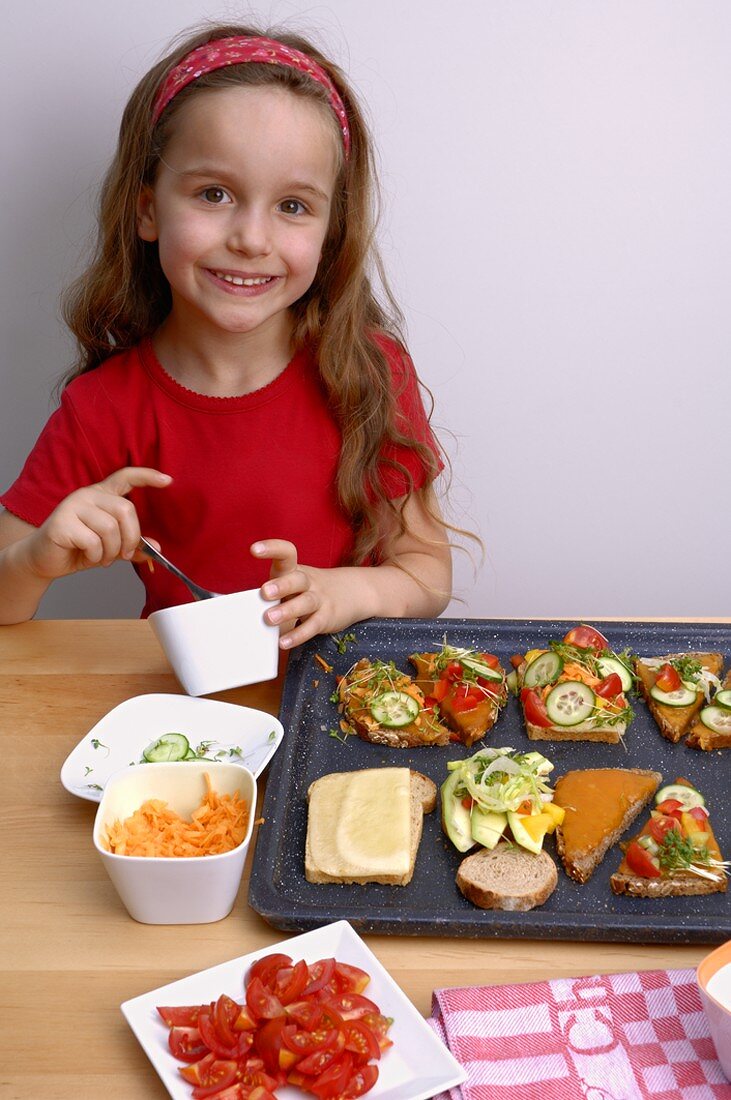 Girl with open sandwiches and vegetables