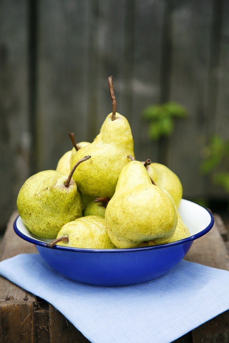 Fresh pears in blue dish on wooden crate