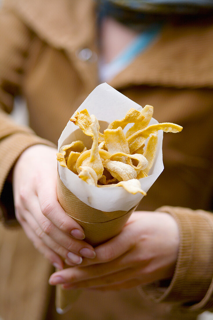 Woman holding pork crostoli in paper cone