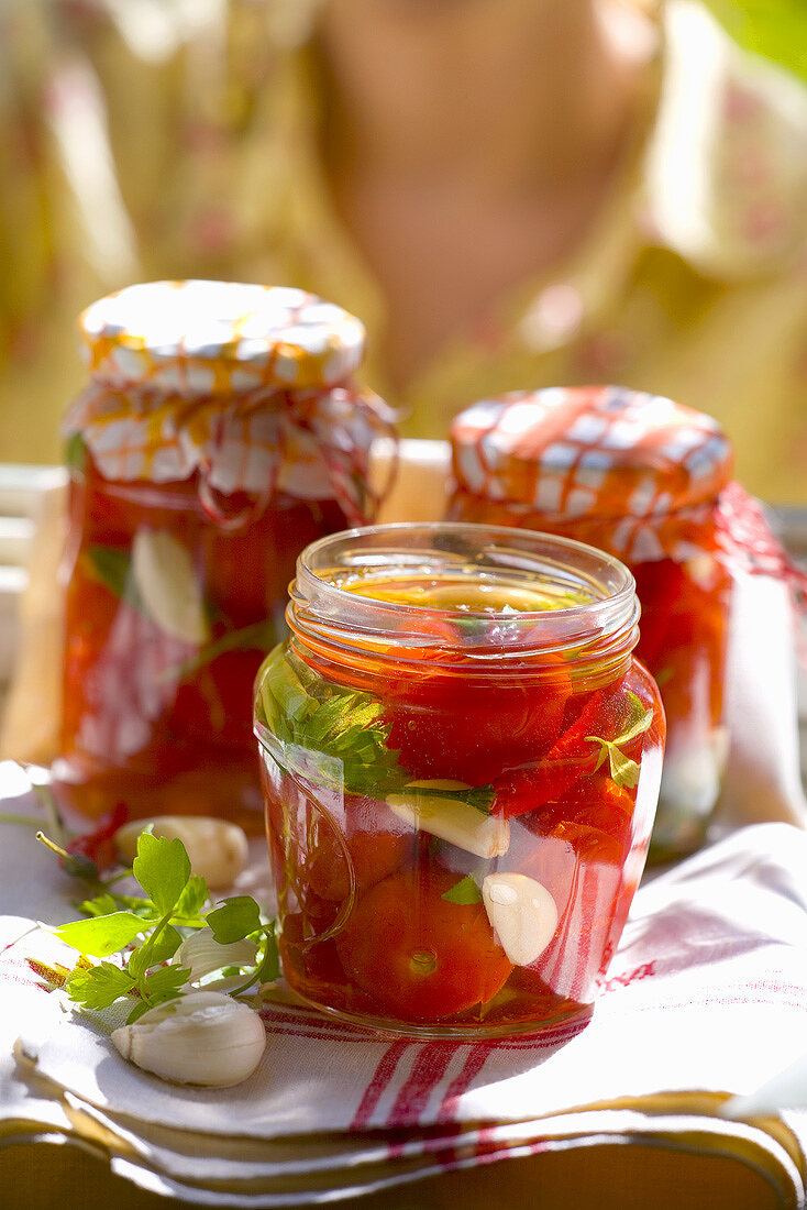 Eingelegte Tomaten in Einmachgläsern, Frau im Hintergrund