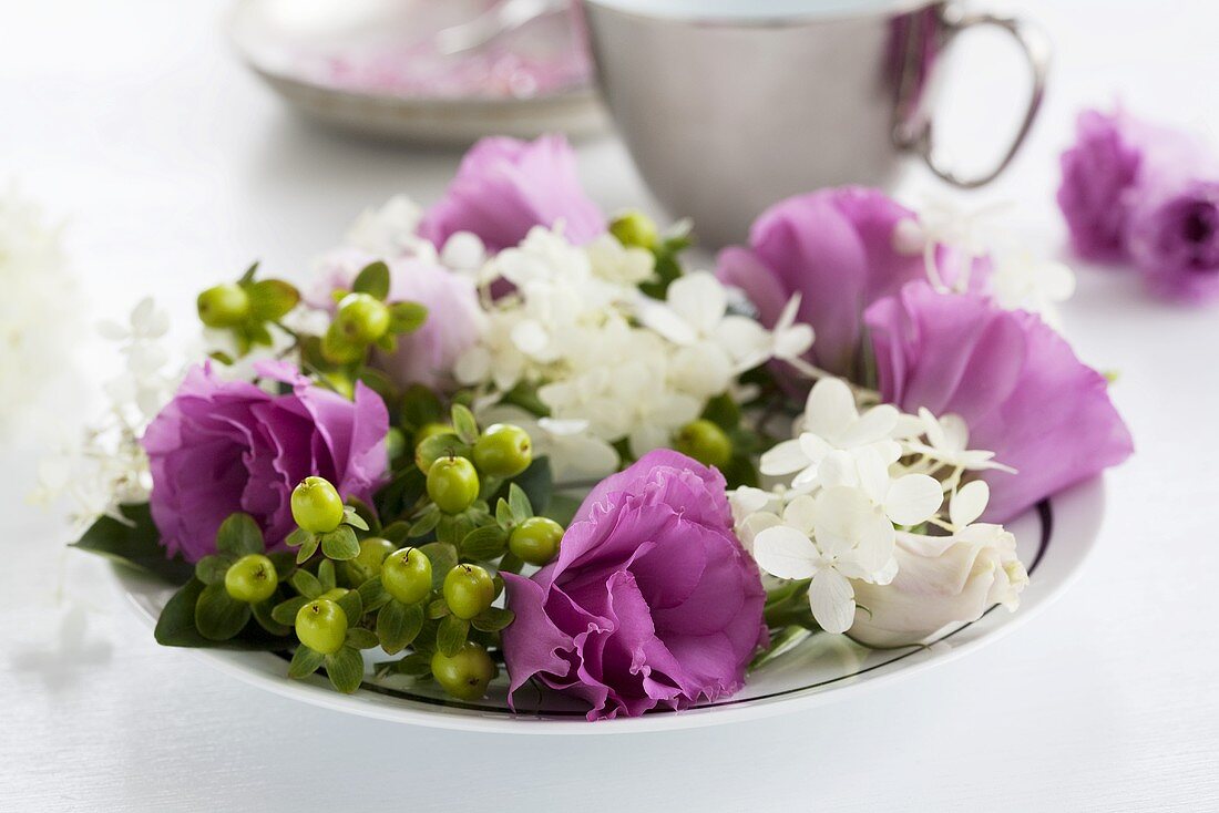 Kränzchen aus Lisianthus, Schneeball und Johanniskrautbeeren auf Teller