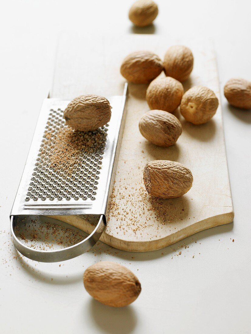 Nutmeg seeds with a grater on a chopping board