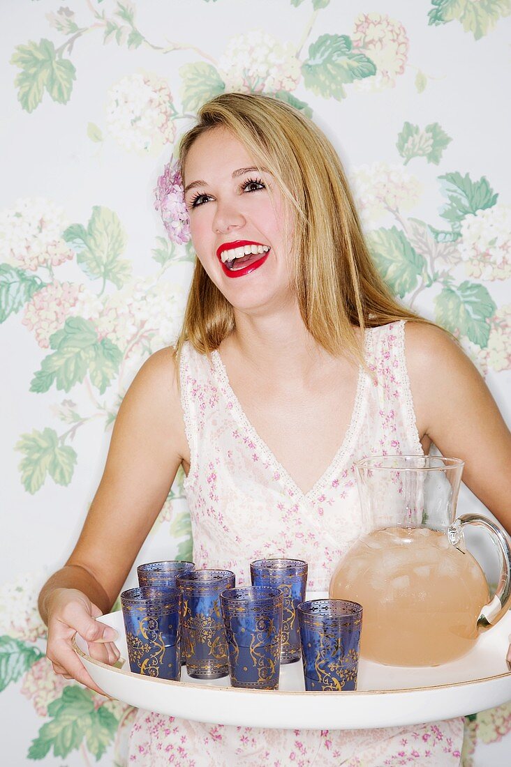 A girl holding a tray with glasses and ginger cordial