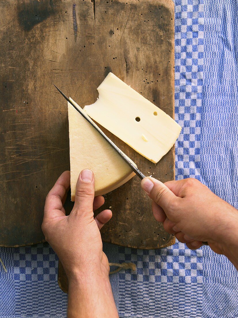 Cutting slices of raclette cheese