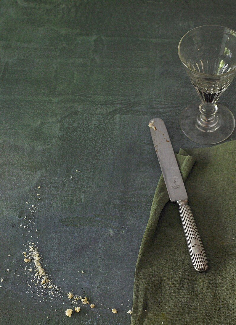 Bread curmbs, serviette, knife and a wine glass