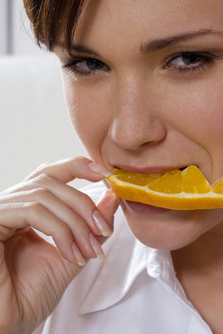 Junge Frau isst Orangenscheibe
