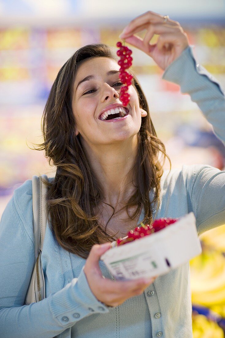 Junge Frau mit roten Johannisbeeren in einem Supermarkt