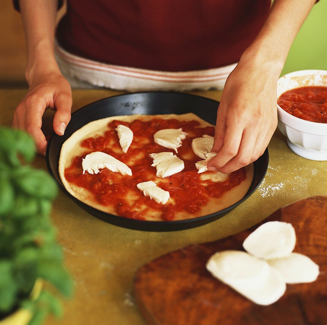 Making Pizza Margherita (covering with mozzarella)