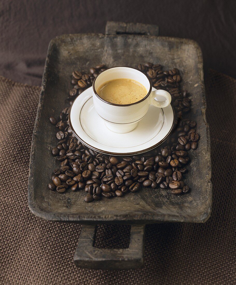 Eine Tasse Espresso auf Holzschale mit Kaffeebohnen