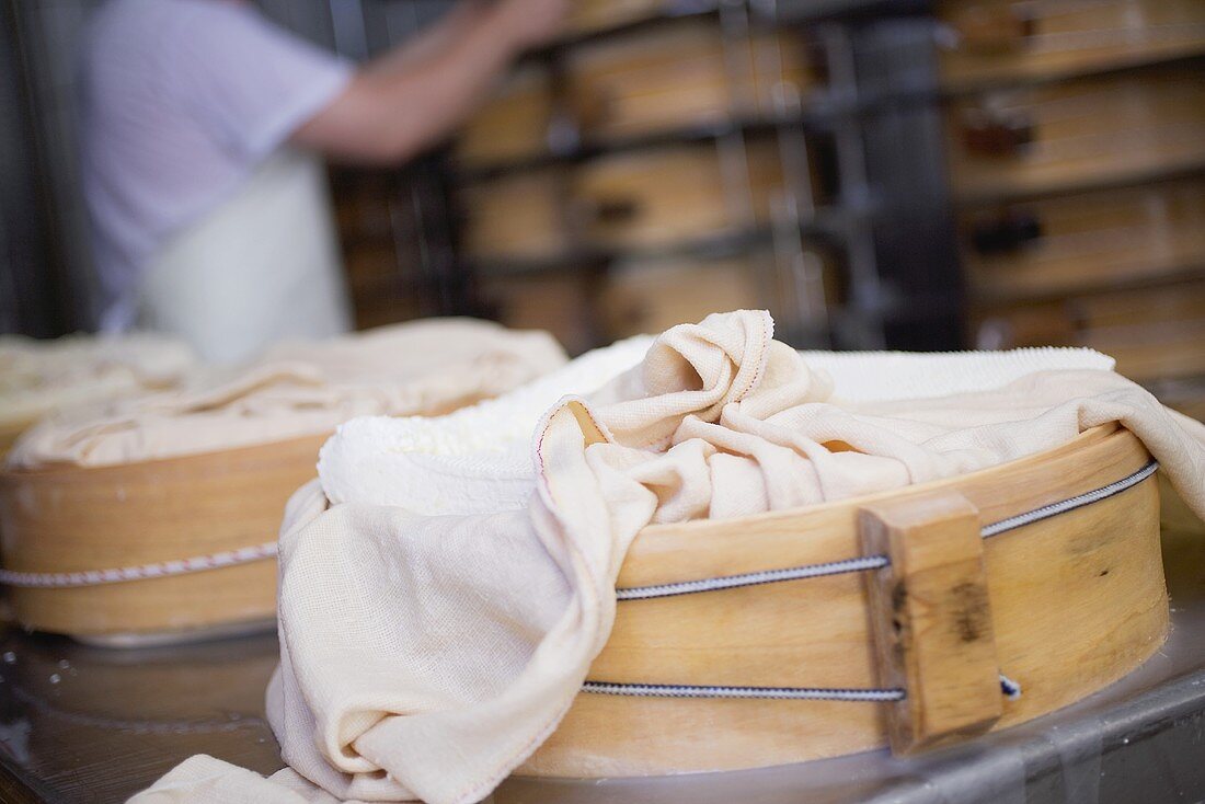Wrapped cheeses being stored in round wooden moulds
