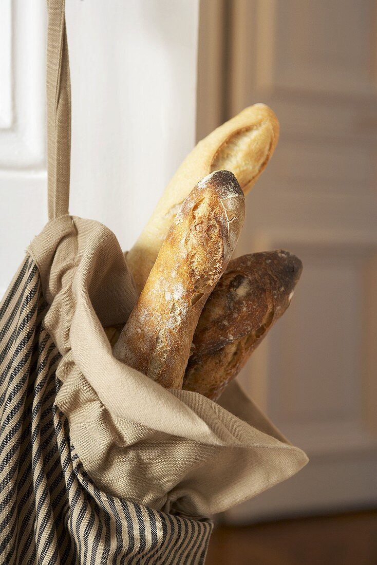 Baguettes in Stofftasche an einer Wohnungstür (Close Up)