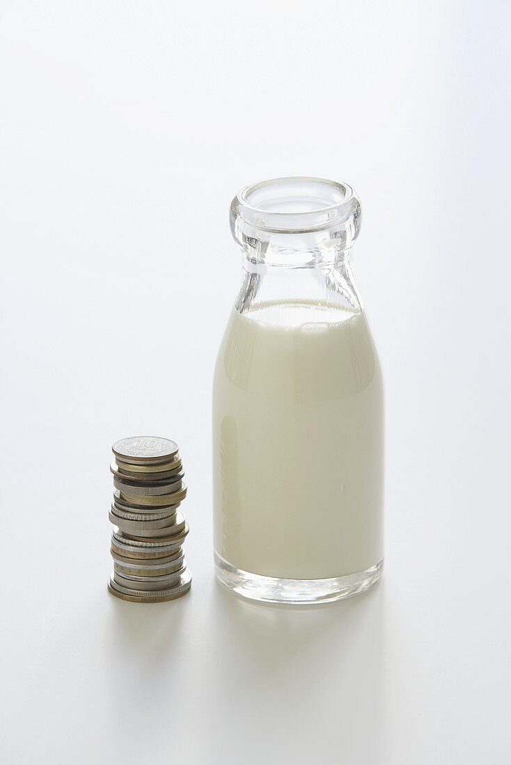 Flasche Milch und gestapelte Euromünzen