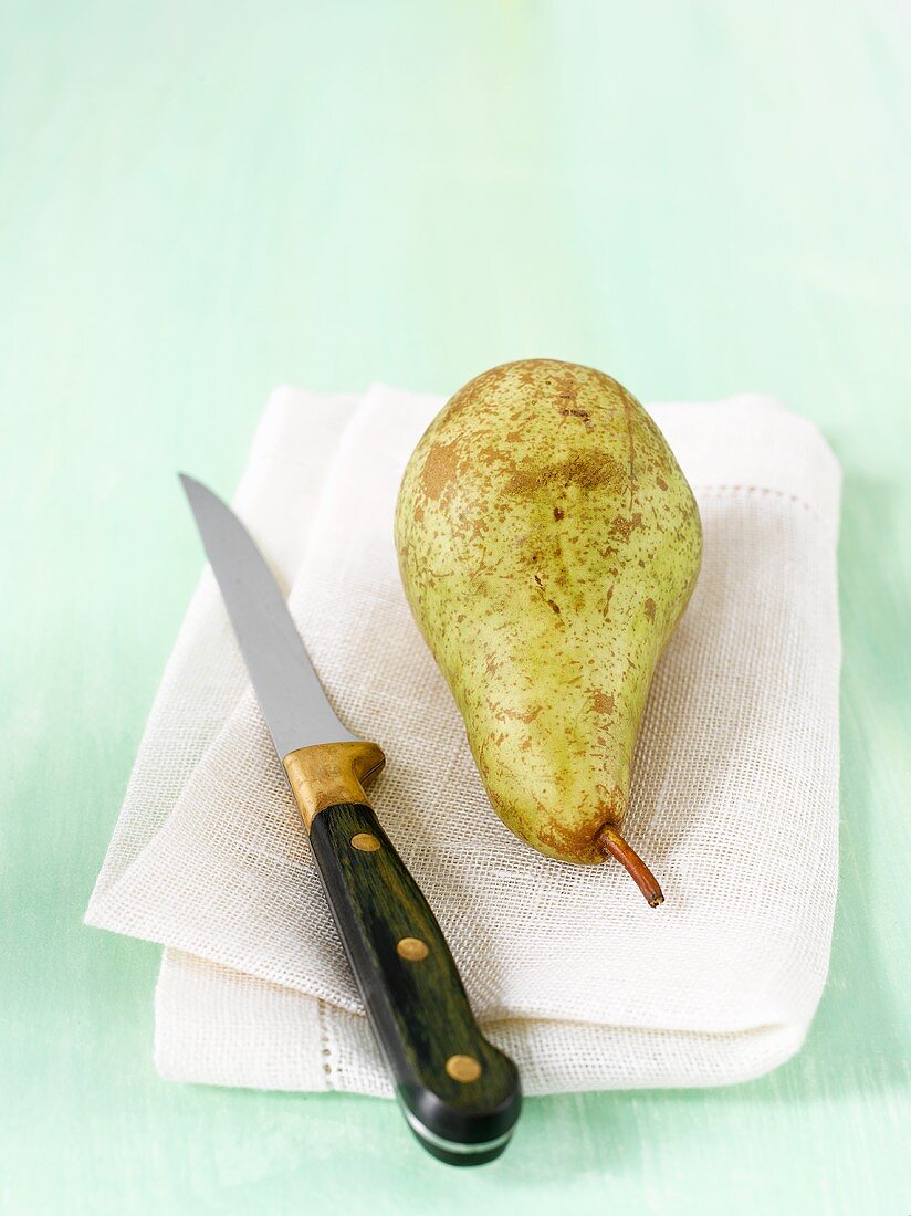 Eine Birne auf Stoffserviette mit Messer