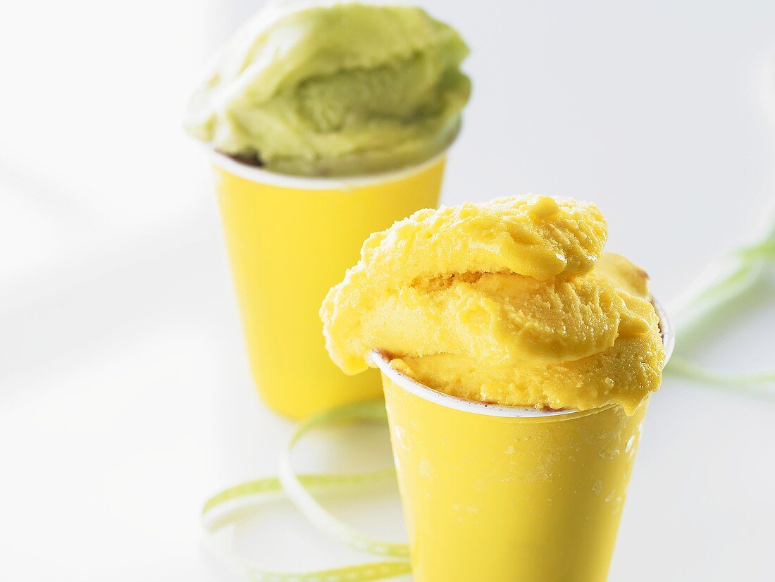 Mango ice cream and pistachio ice cream in yellow tubs