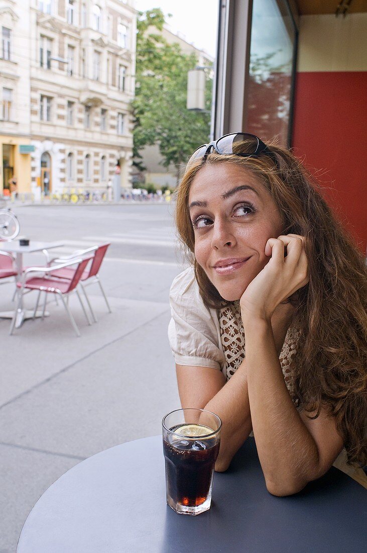 Frau mit einem Glas Cola im Strassencafe