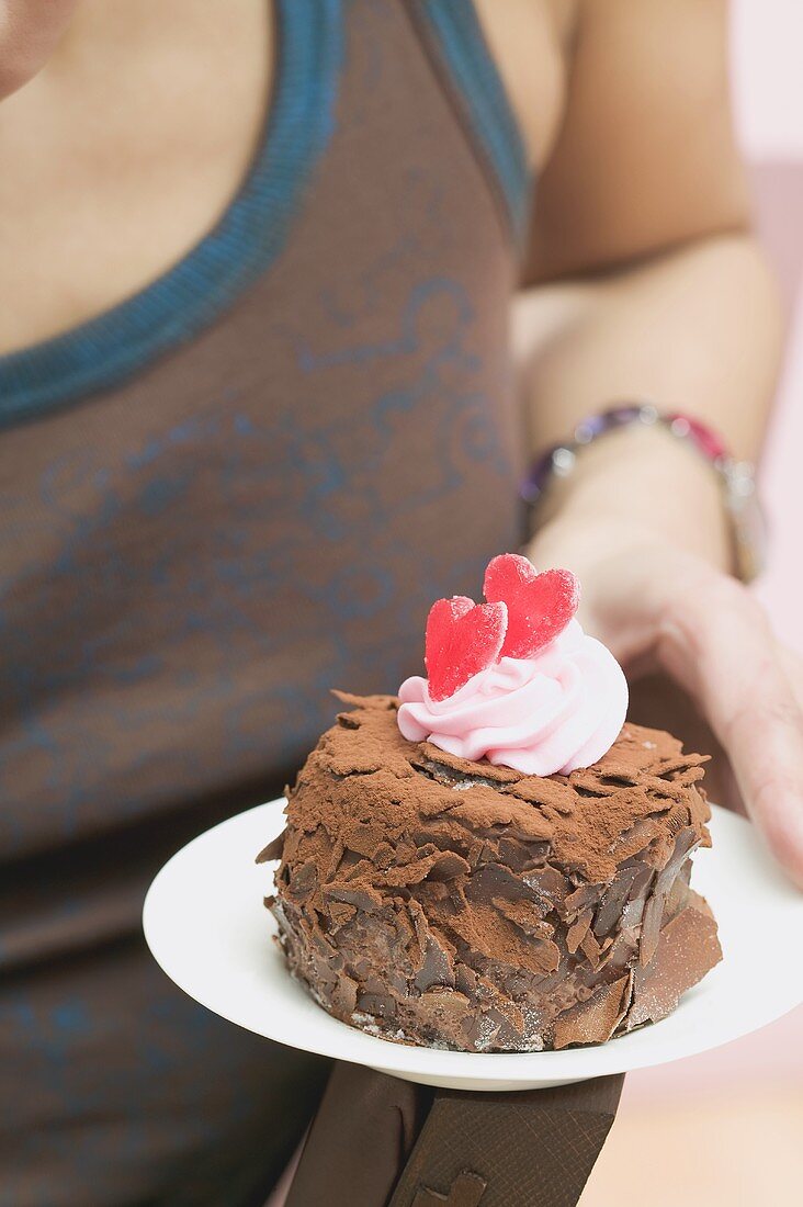 Frau hält Schokoladentörtchen mit roten Herzen